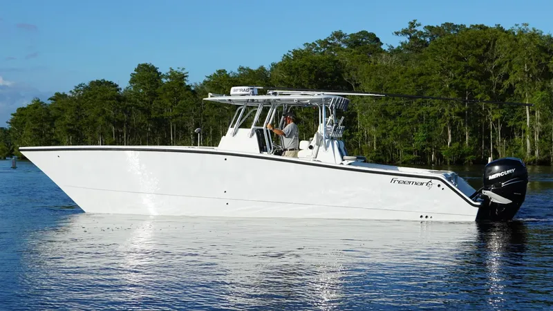 Slide: The Image of 2023 Freeman 34VH boat on a calm lake with forested background. - 9