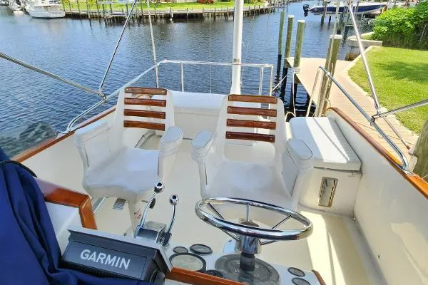 Slide: The Image of 1987 Duffy Flybridge Cruiser helm with Garmin system, docked by a serene waterfront. - 17