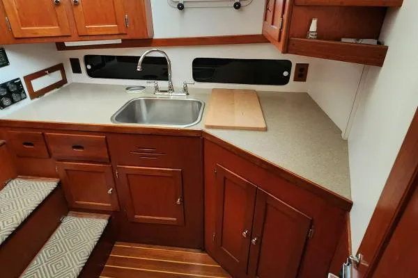 Slide: The Image of 1987 Duffy Flybridge Cruiser kitchen with wooden cabinets, sink, and countertop. - 26