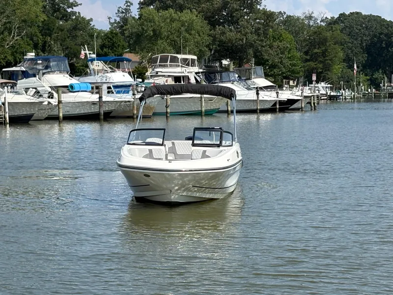 Slide: The Image of 2022 Bayliner VR6 Bowrider OB on calm water near a marina with other boats. - 2