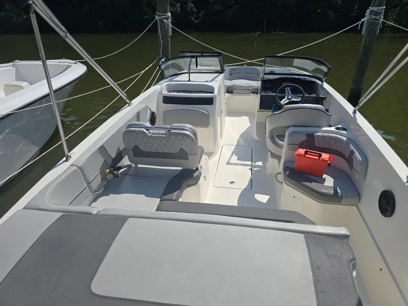 Slide: The Image of 2022 Bayliner VR6 Bowrider OB interior with seating and steering wheel, docked on calm water. - 4