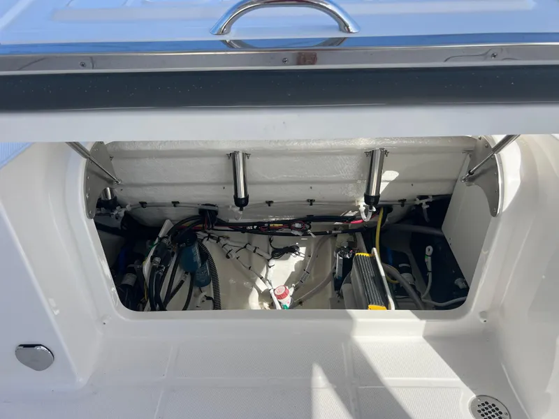 Slide: The Image of 2025 Robalo R257 Dual Console boat storage compartment with visible wiring and components. - 25