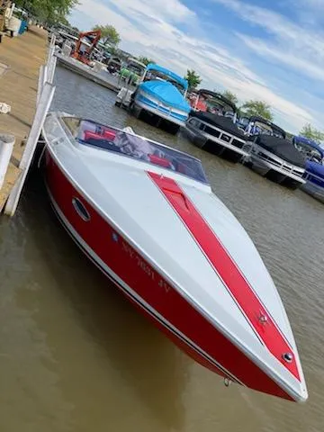 Slide: The Image of 1988 Donzi R23 speedboat docked at marina, red and white design, surrounded by other boats. - 2