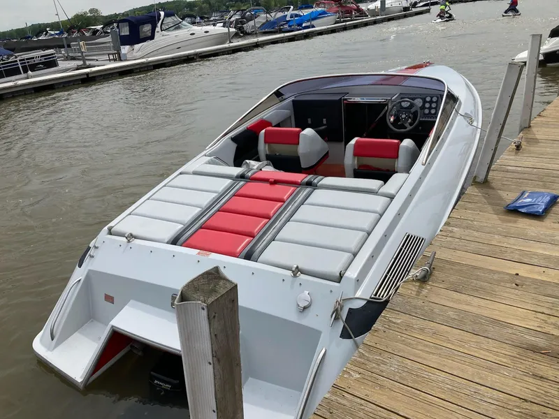 Slide: The Image of 1988 Donzi R23 speedboat docked, featuring red and gray seating, with other boats in the background. - 3