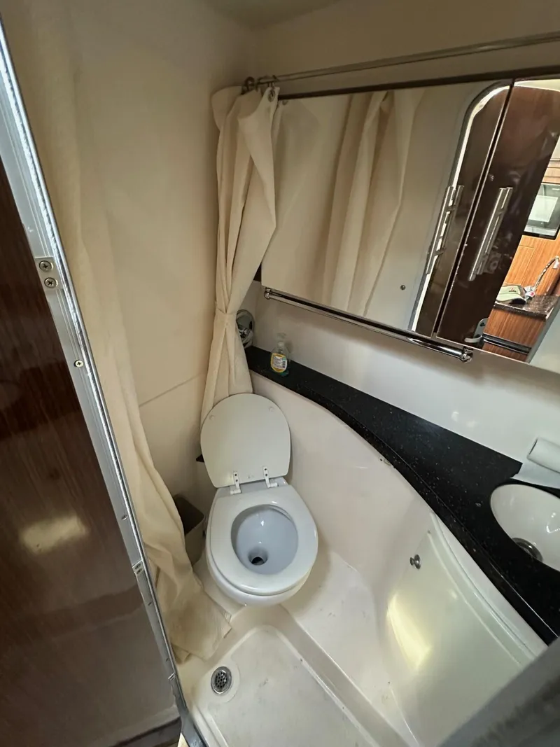 Slide: The Image of Compact bathroom in a 2013 Regal 28 Express boat, featuring a toilet and shower. - 9