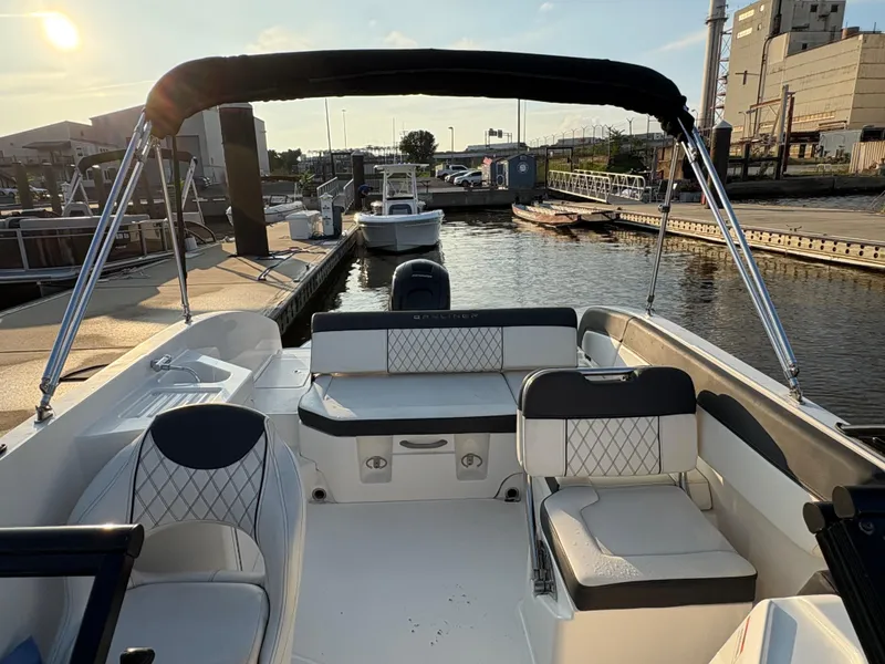 Slide: The Image of 2022 Bayliner DX 2200 boat interior at marina, featuring seating and canopy. - 5