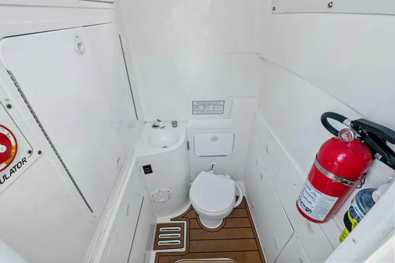 Slide: The Image of 2012 Regulator 32 FS boat bathroom with toilet, sink, and fire extinguisher. - 13