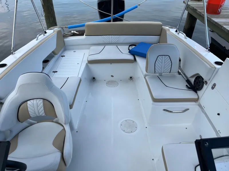 Slide: The Image of 2022 Glastron GTD 220 boat interior with white and beige seating, docked by the water. - 5