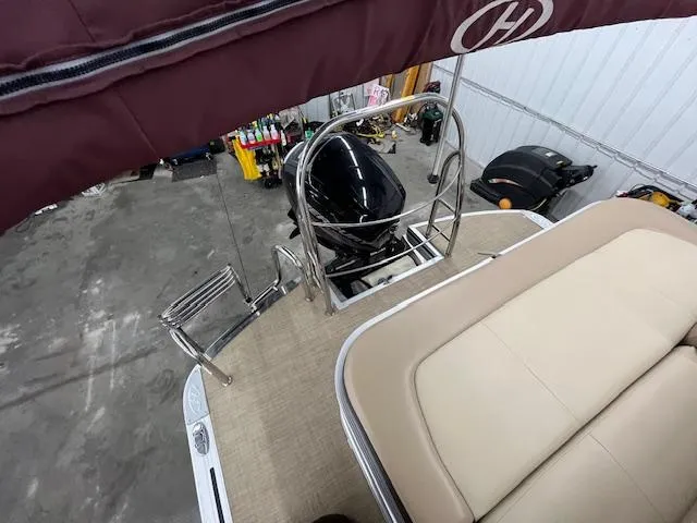 Slide: The Image of 2016 Harris Solstice 220 SL boat interior with motor, beige seating, and maroon canopy. - 8