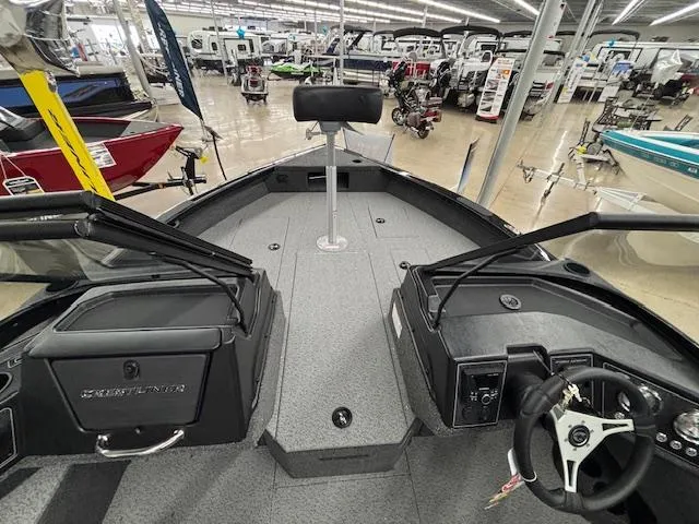 Slide: The Image of 2025 Crestliner 2050 Fish Hawk boat interior at showroom, featuring steering wheel and seating. - 12
