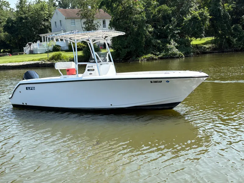Slide: The Image of 2023 Aquasport 2200 Center Console boat on a calm river near a house. - 0