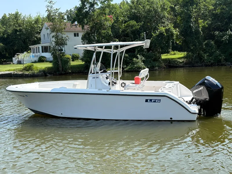 Slide: The Image of 2023 Aquasport 2200 Center Console boat on a calm river near a house. - 1