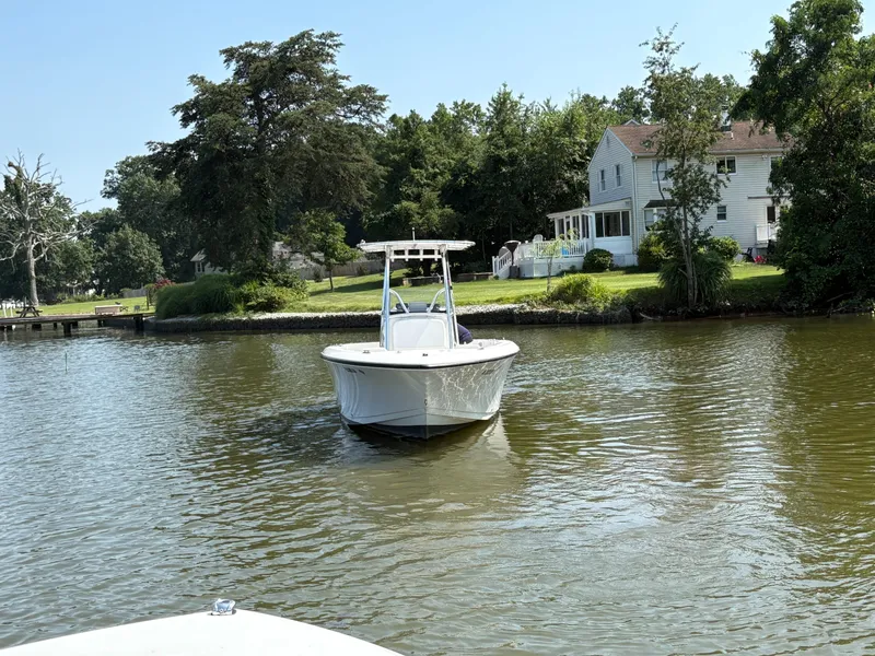 Slide: The Image of 2023 Aquasport 2200 Center Console boat on a calm river near a house. - 2