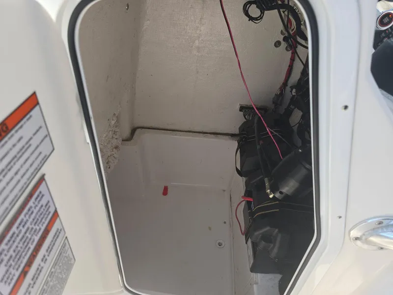 Slide: The Image of 2023 Aquasport 2200 Center Console storage compartment with wiring and battery setup. - 4