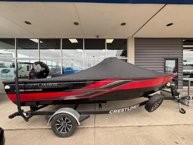 The Image of 2025 Crestliner 1850 Super Hawk WT JS boat with cover on trailer, displayed outdoors. - 1