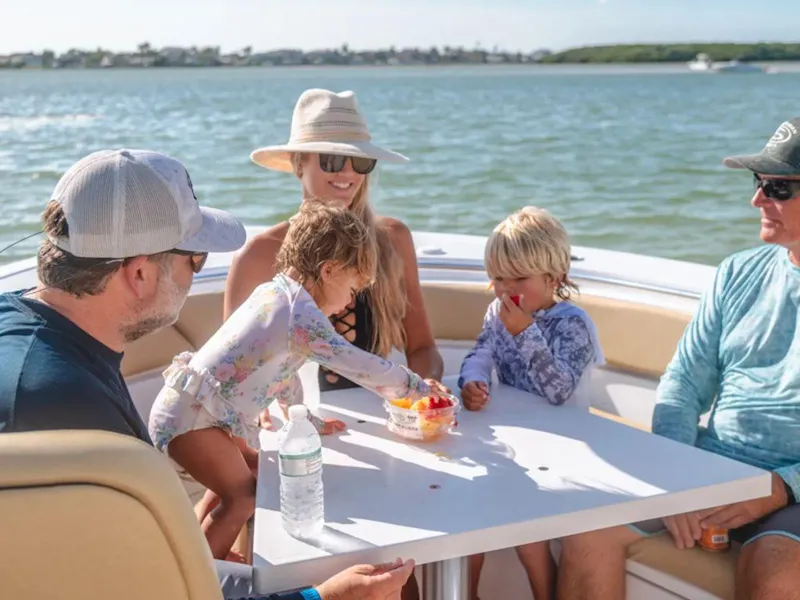 Slide: The Image of Family enjoying a day on a 2026 Sportsman Heritage 261 boat, sharing snacks. - 4