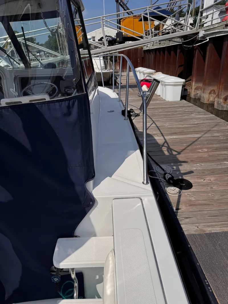 Slide: The Image of 2004 Glacier Bay 2680 Coastal Runner docked, featuring sleek design and blue canopy. - 10