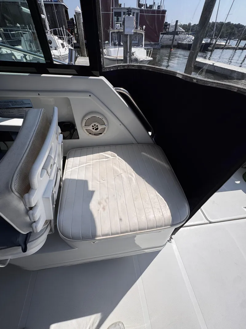Slide: The Image of 2004 Glacier Bay 2680 Coastal Runner boat interior with white seating and marina view. - 23