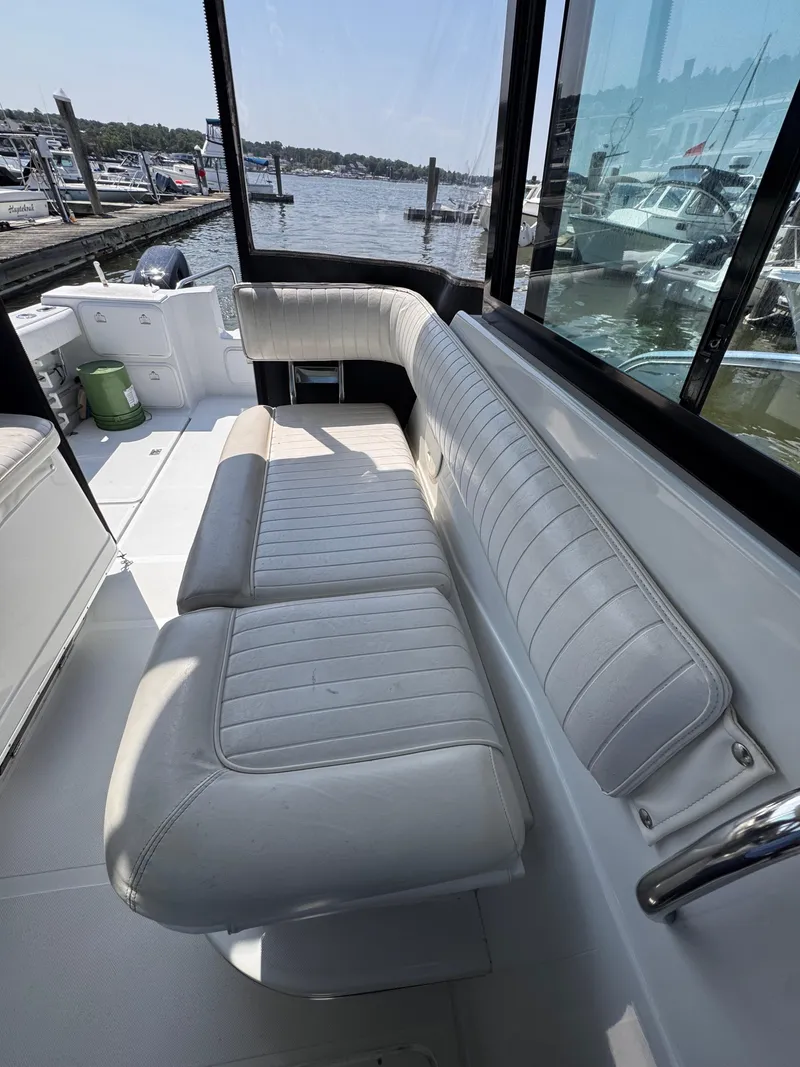 Slide: The Image of 2004 Glacier Bay 2680 Coastal Runner boat interior with white seating and marina view. - 24