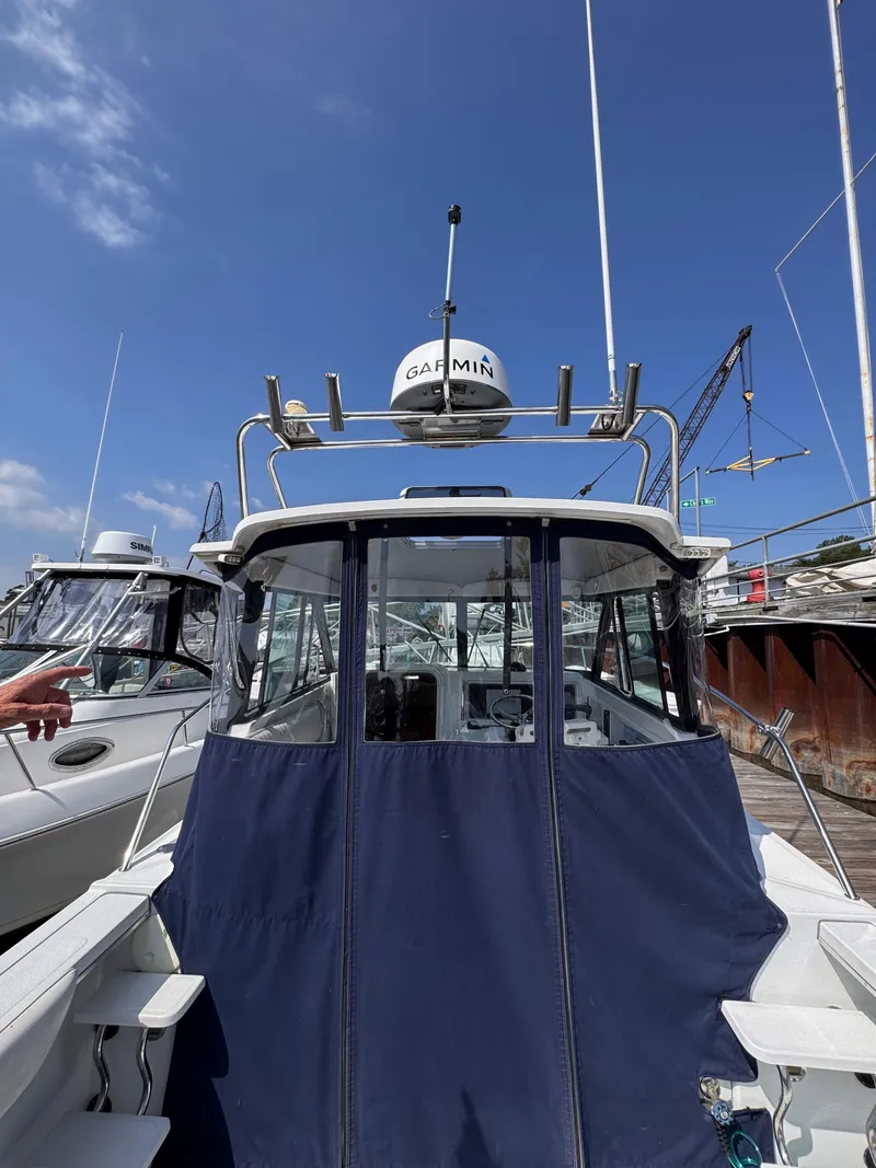 Slide: The Image of 2004 Glacier Bay 2680 Coastal Runner boat with Garmin equipment, docked under clear blue sky. - 8