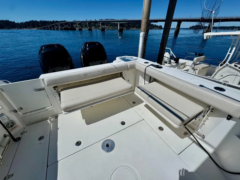 Slide: The Image of 2018 Boston Whaler 285 Conquest boat deck with seating, overlooking a scenic waterway and bridge. - 12