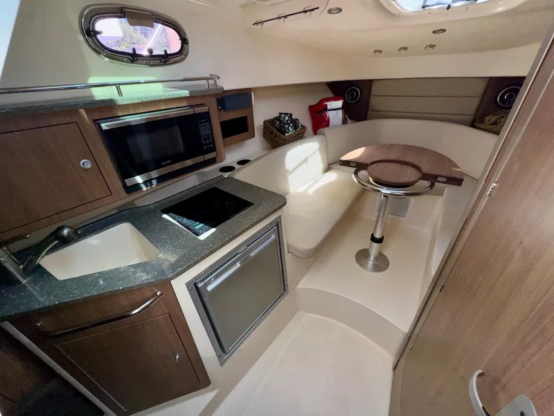 Slide: The Image of 2018 Boston Whaler 285 Conquest cabin interior with kitchenette and seating area. - 20