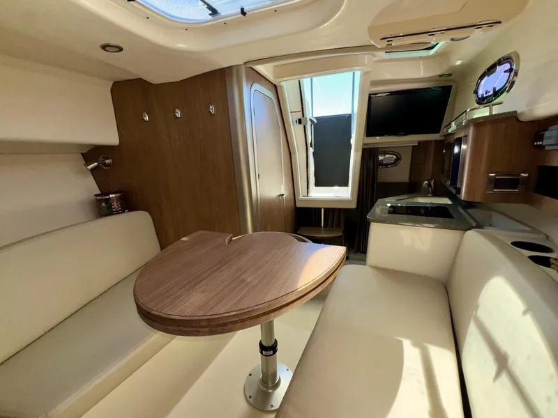 Slide: The Image of 2018 Boston Whaler 285 Conquest cabin interior with seating, table, and kitchenette. - 21