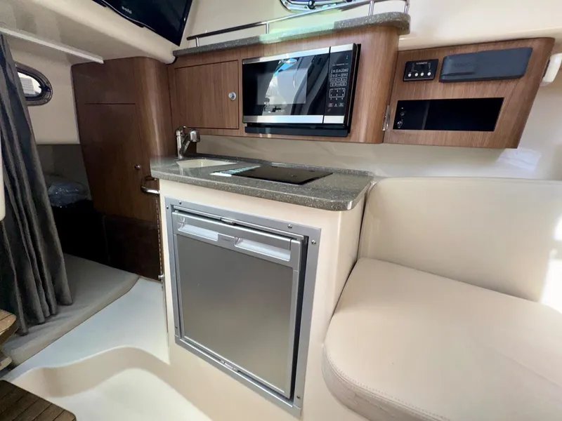 Slide: The Image of 2018 Boston Whaler 285 Conquest cabin interior with kitchenette and seating area. - 22