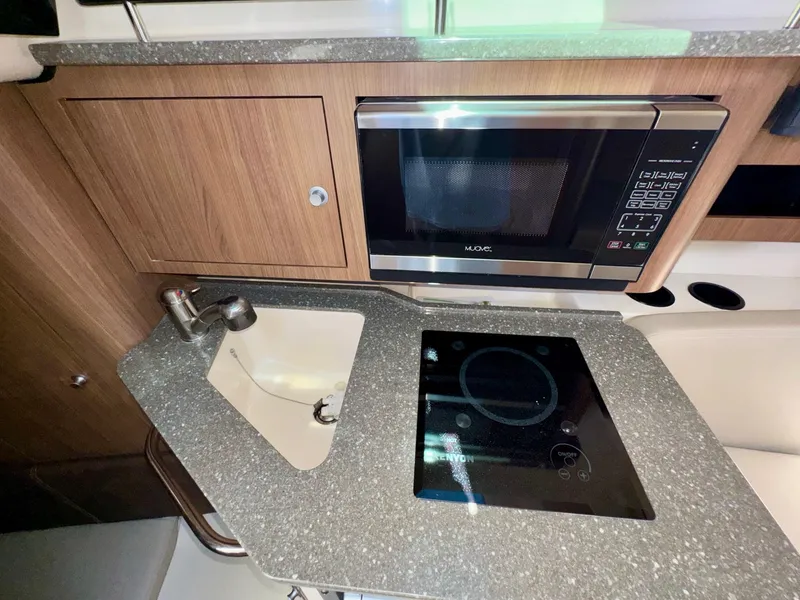 Slide: The Image of 2018 Boston Whaler 285 Conquest galley with microwave, sink, and cooktop. - 23