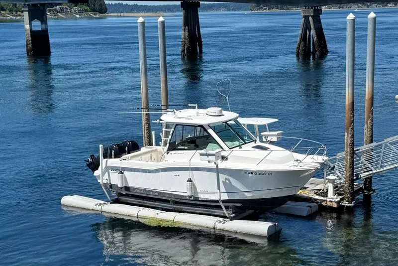 Slide: The Image of 2018 Boston Whaler 285 Conquest boat docked on calm water near a bridge. - 31