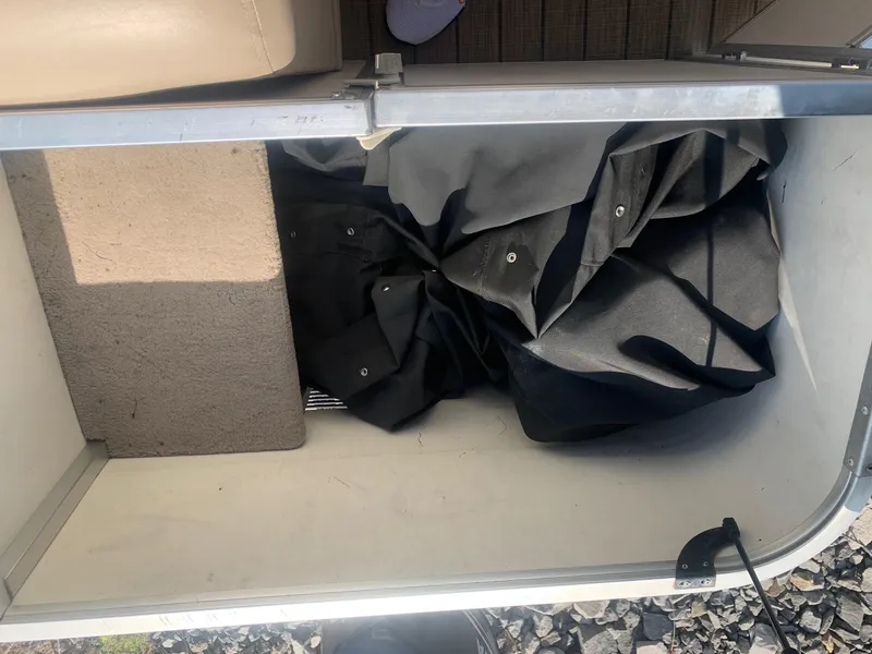 Slide: The Image of Storage compartment in a 2006 Sun Tracker PARTY BARGE 21, containing a folded black cover. - 13