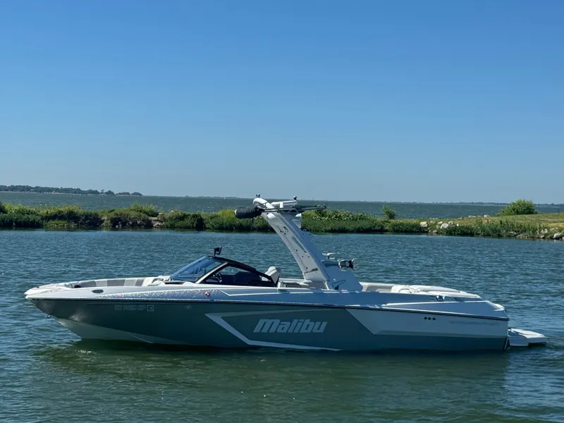 The Image of 2022 Malibu Wakesetter 24 MXZ boat on calm water under clear blue sky. - 1