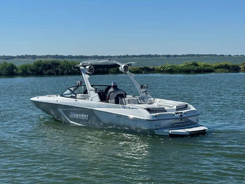 Slide: The Image of 2022 Malibu Wakesetter 24 MXZ boat cruising on a sunny lake. - 2