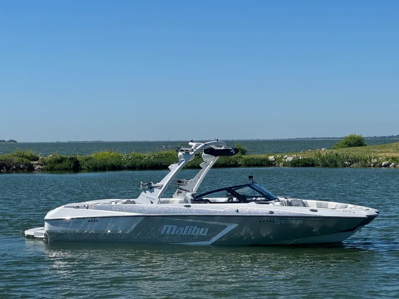 Slide: The Image of 2022 Malibu Wakesetter 24 MXZ boat on a calm lake under clear blue sky. - 4