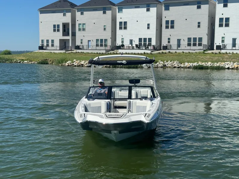 Slide: The Image of 2022 Malibu Wakesetter 24 MXZ boat on water near modern waterfront homes. - 7