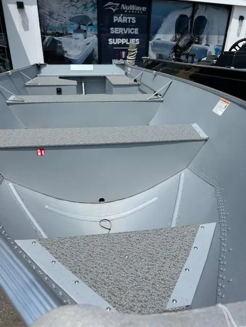 Slide: The Image of 2026 Lund WC-16 boat interior at dealership, showcasing seating and storage. - 2