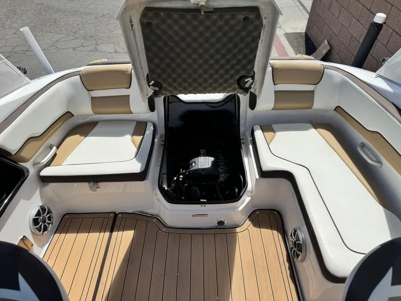 Slide: The Image of 2022 Yamaha Boats AR 195 S interior with open engine compartment, cushioned seating, and teak flooring. - 16
