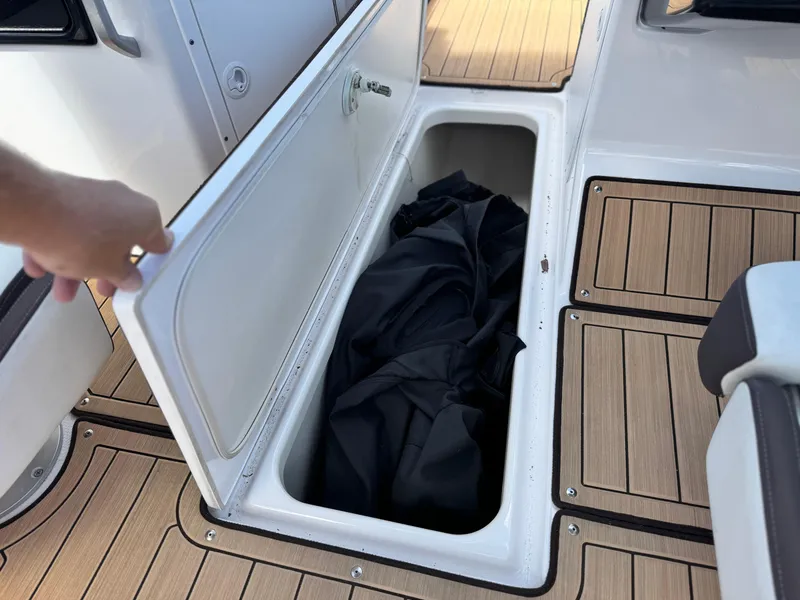 Slide: The Image of 2022 Yamaha Boats AR 195 S storage compartment with open lid and black cover inside. - 19