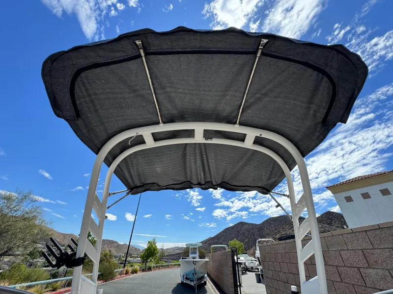 Slide: The Image of 2022 Yamaha Boats AR 195 S with canopy, parked under a clear blue sky. - 30