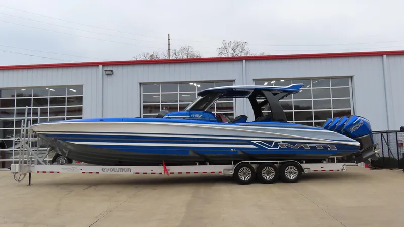 Slide: The Image of 2025 MTI 42V boat in blue on a trailer outside a garage. - 1