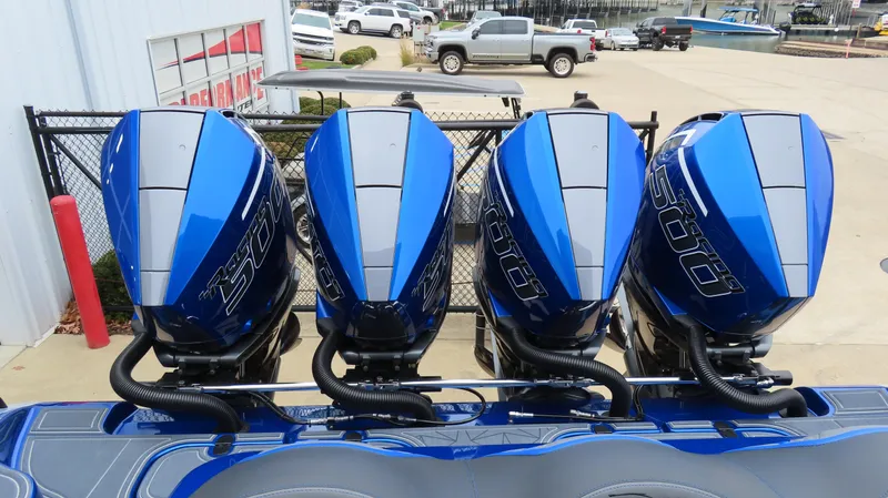 Slide: The Image of Four blue outboard motors on a 2025 MTI 42V boat, parked near a fence. - 8