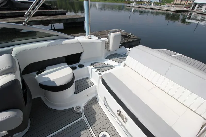 Slide: The Image of 2015 Cruisers Sport Series 238 Bow Rider interior with seating and storage, docked by calm water. - 13