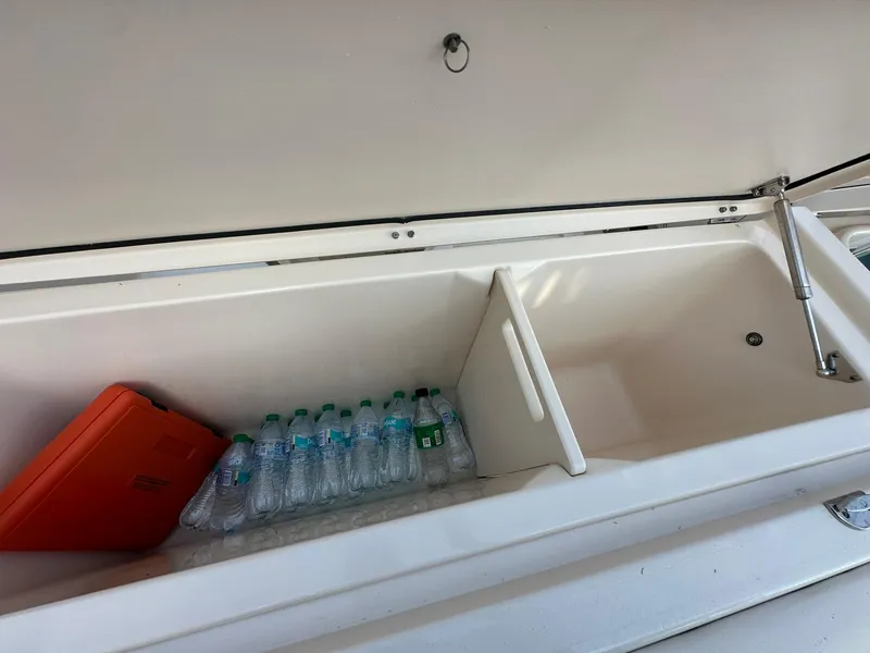 Slide: The Image of 2024 Grady-White Freedom 335 storage compartment with water bottles and an orange case. - 11