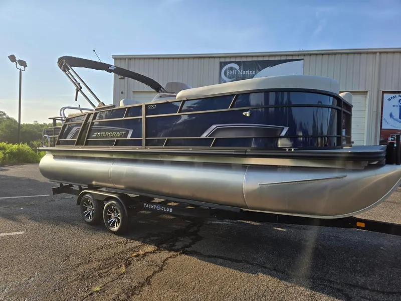 Slide: The Image of 2026 Starcraft EX22QDH pontoon boat on trailer, parked outside a marine shop. - 3
