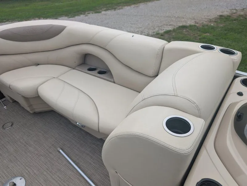 Slide: The Image of 2017 Sylvan Mirage Cruise 8520 CR boat interior with beige seating and cup holders. - 8