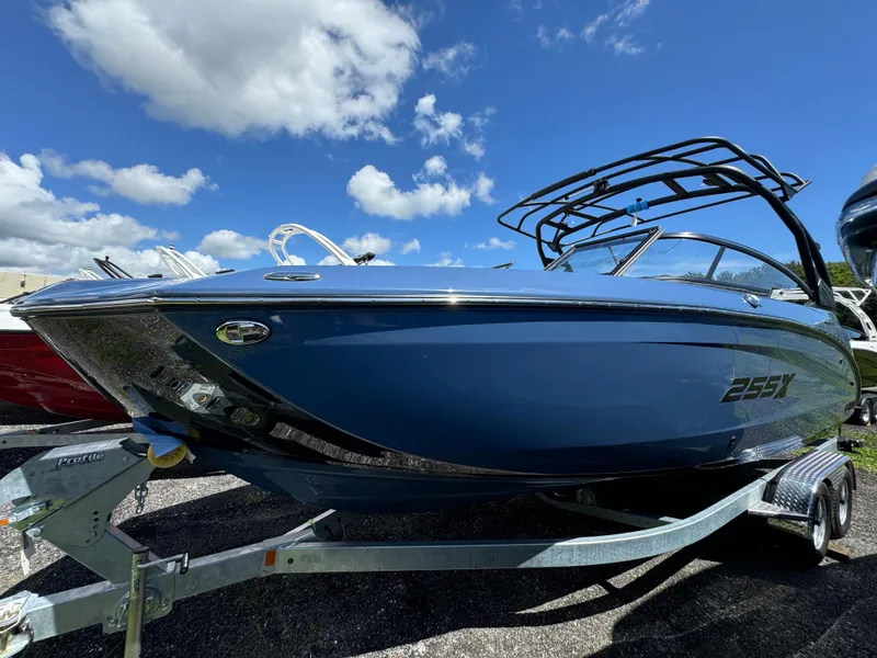 Slide: The Image of 2024 Yamaha Boats 255XD in blue, parked on a trailer under a clear sky. - 2