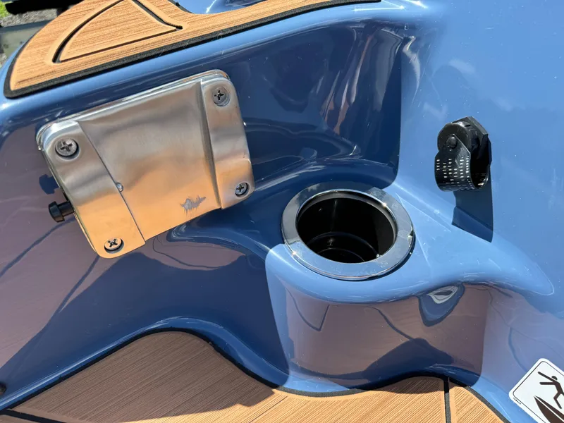 Slide: The Image of 2024 Yamaha Boats 255XD, blue deck detail with cup holder and metal fixture. - 9