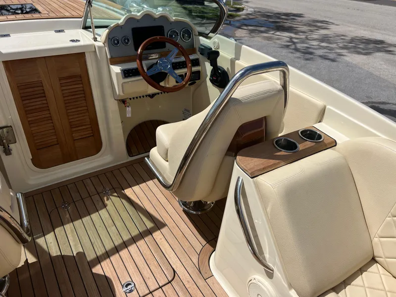 Slide: The Image of 2019 Chris-Craft Corsair 27 interior with wooden accents and beige seating. - 9