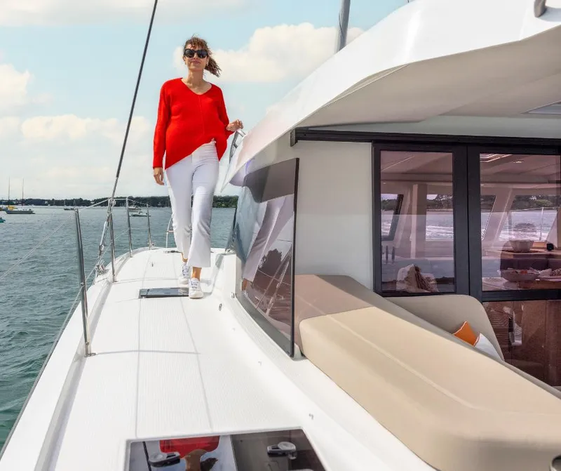 The Image of Woman walking on 2025 Fountaine Pajot NEW 41 yacht deck, wearing red and white outfit. - 0