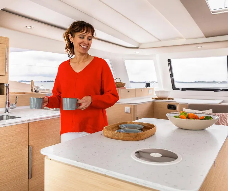 Slide: The Image of Woman in Fountaine Pajot NEW 41 yacht kitchen, holding mugs, 2025 model. - 14